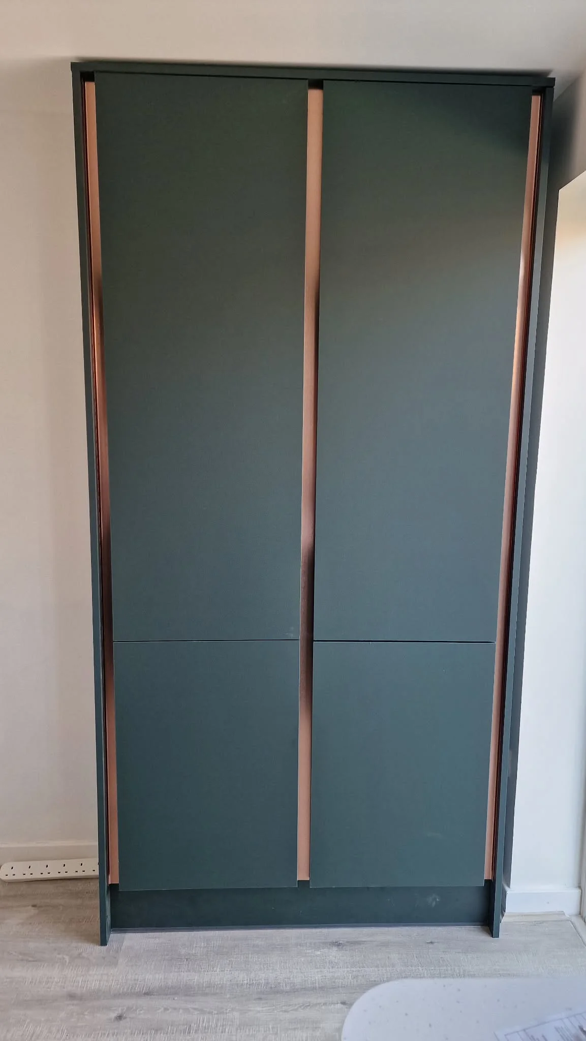 Floor-to-ceiling fitted wardrobe with dark finish and copper trim